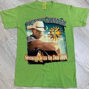 Könnte beinhalten: Hellgrünes T-Shirt mit einer Grafik von Kenny Chesney mit Cowboyhut. Die Grafik enthält den Text "KENNY CHESNEY" und "SOMEWHERE IN THE SUN TOUR 2005". Das T-Shirt hat einen Rundhalsausschnitt.