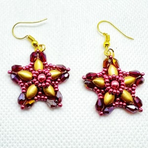 Può includere: Un paio di orecchini a forma di stella dorati e bordeaux con un design a perline.