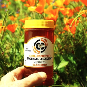 Peut inclure: Un pot en verre de miel de sauge cru et non filtré avec un couvercle jaune. L'étiquette indique "California Tactical Academy" et "100% Naturel U.S. Grade A Produit des États-Unis."