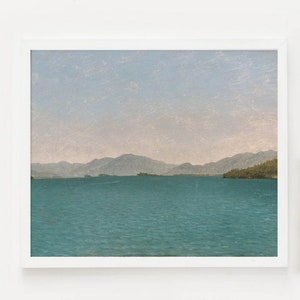 May include: A white frame with a landscape photograph of a lake and mountains. A gold frame with a photograph of a baby's feet. A gold metal stand with a round top and three legs. A white ceramic vase with green leafy plants.