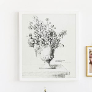 Op de afbeelding: Een zwart-witte tekening van een boeket bloemen in een vaas, met een citaat over het leven en een kleine foto van babyvoetjes in een gouden lijst die aan een witte muur hangt.