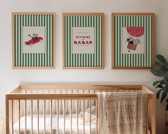 Puede incluir: Tres impresiones enmarcadas con bordes rayados verdes y blancos. Las impresiones presentan ilustraciones de un coche rojo, un globo aerostático y el texto "Histoire de Babar". Las impresiones están colgadas en una pared blanca sobre una cuna de madera con una manta blanca.