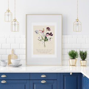 May include: A framed botanical print featuring a watercolor illustration of sweet pea flowers in shades of purple, pink, and white. The artwork is set against a cream-colored background and includes handwritten text. The frame is gold, and the print is displayed in a kitchen setting.