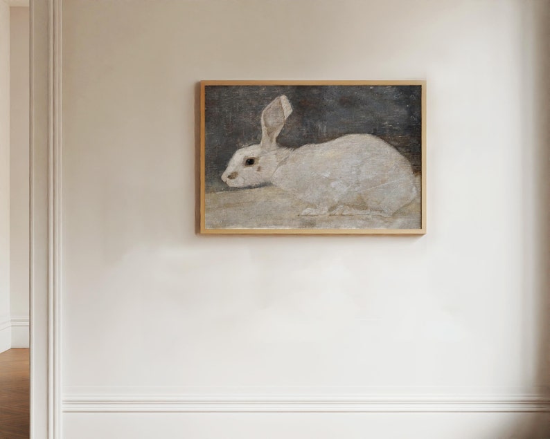 This vintage painting of a white rabbit is horizontal. The white rabbit is against a dark gray background with an off white ground. We see him in profile with his ears high.