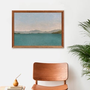 May include: A framed painting of a landscape with a body of water and mountains in the distance. The water is a light blue-green color and the mountains are a dark green color. The sky is a light blue color.