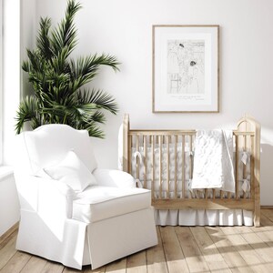 K&ouml;nnte beinhalten: Ein wei&szlig;er Kinderzimmer-Schaukelstuhl mit einem wei&szlig;en Kissen und ein Holz-Kinderbett mit einer wei&szlig;en gesteppten Decke und einem wei&szlig;en R&uuml;schenrock. Ein gerahmtes Schwarzwei&szlig;-Bild h&auml;ngt an der Wand hinter dem Kinderbett.