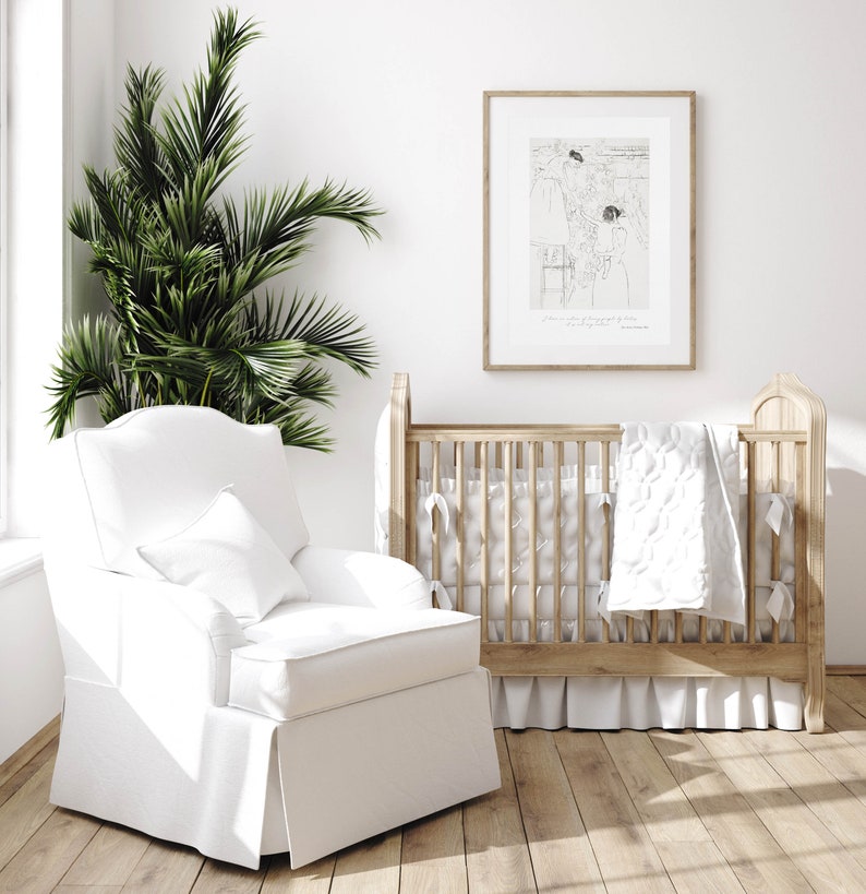 K&ouml;nnte beinhalten: Ein wei&szlig;er Kinderzimmer-Schaukelstuhl mit einem wei&szlig;en Kissen und ein Holz-Kinderbett mit einer wei&szlig;en gesteppten Decke und einem wei&szlig;en R&uuml;schenrock. Ein gerahmtes Schwarzwei&szlig;-Bild h&auml;ngt an der Wand hinter dem Kinderbett.