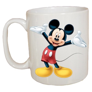 May include: White ceramic mug with a colorful image of Mickey Mouse in his signature red shorts and yellow shoes. Mickey is smiling and has his arms outstretched.