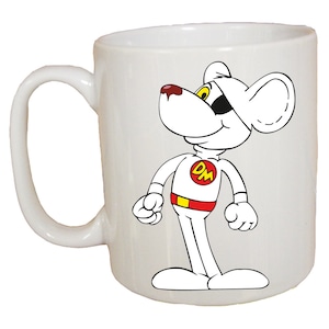 May include: White ceramic mug featuring a cartoon image of a white mouse dressed in a red and yellow superhero costume with the letters "DM" on the chest. The mouse has a black eye patch and is looking to the right.