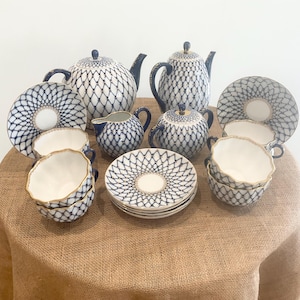 May include: A vintage porcelain tea set with a blue and white lattice pattern. The set includes a teapot, creamer, sugar bowl, and four teacups and saucers.