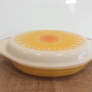 May include: A yellow oval baking dish with a white lid. The lid has a yellow and orange sunflower design.