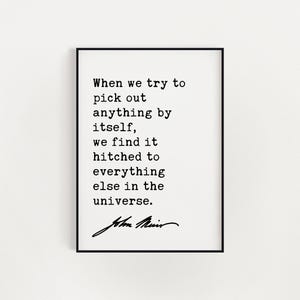 May include: A rectangular wall art print featuring black typewriter-style text on a white background. The quote reads: When we try to pick out anything by itself, we find it hitched to everything else in the universe. Signed by John Muir.