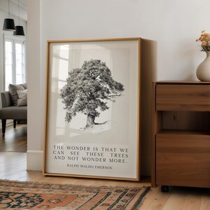 Może przedstawiać: Oprawiony wydruk z czarno-białą ilustracją drzewa i cytatem: "THE WONDER IS THAT WE CAN SEE THESE TREES AND NOT WONDER MORE. RALPH WALDO EMERSON." Rama jest w kolorze jasnobrązowym.