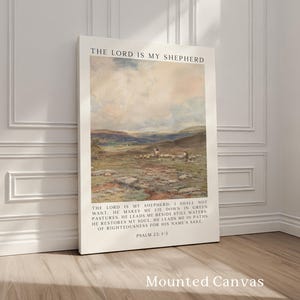 May include: Mounted canvas art print featuring a pastoral landscape with sheep and figures. The text "THE LORD IS MY SHEPHERD" is at the top, with Psalm 23:1-3 below the image. The canvas is leaning against a white wall.