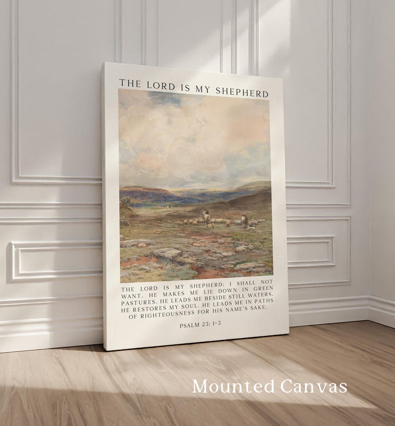 May include: Mounted canvas art print featuring a pastoral landscape with sheep and figures. The text "THE LORD IS MY SHEPHERD" is at the top, with Psalm 23:1-3 below the image. The canvas is leaning against a white wall.