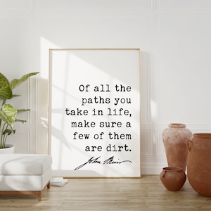 Op de afbeelding: Een zwart-wit typografieprint met een citaat van John Muir: "Van alle paden die je in het leven bewandelt, zorg ervoor dat er een paar van aarde zijn."