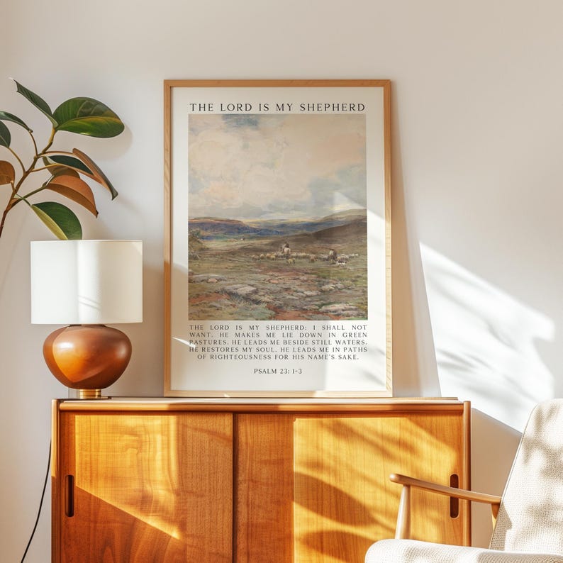 May include: A framed print with the text "THE LORD IS MY SHEPHERD" at the top. The artwork depicts a landscape with sheep grazing in a field. Below the image is a Bible verse from Psalm 23:1-3.
