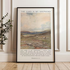 May include: Framed art print featuring a pastoral landscape with sheep and figures. The artwork has a muted color palette of greens, blues, and beige. The text "THE LORD IS MY SHEPHERD" is at the top, with Psalm 23:1-3 below the image.