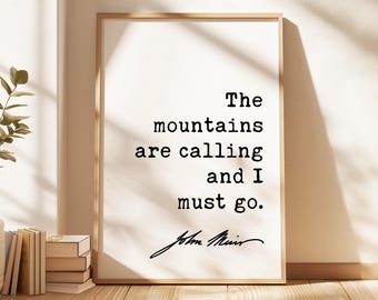 May include: A rectangular wall art print in a light wood frame featuring the black text The mountains are calling and I must go. followed by the signature John Muir on a white background. The print is displayed in a vertical orientation.