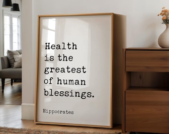 May include: A rectangular framed wall art print featuring the black text Health is the greatest of human blessings. followed by the attribution Hippocrates in a typewriter-style font on a white background, encased in a light wood frame.