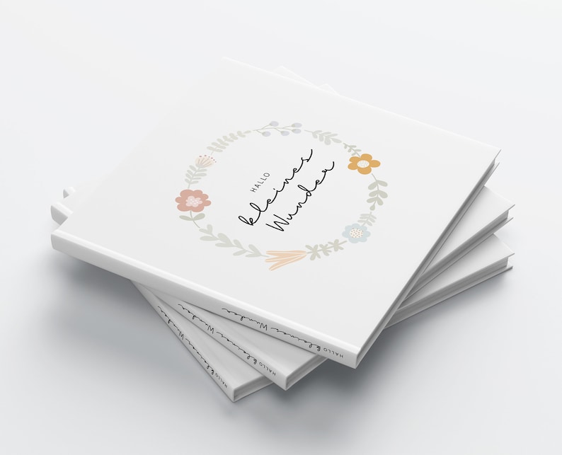 May include: A stack of white books with a floral wreath design and the text "Hallo kleines Wunder" on the cover.