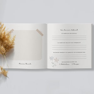 May include: A blank, cream-colored journal with a floral design and the text "Wer deiner Geburt" on the right page. The text continues with "So haben wir uns gef&uuml;hlt", "So haben wir uns auf dich vorbereitet", "Besondere Momente als Mama mit dir schwanger war", "Wir dachten du wirst ein", and a checkbox for "M&auml;dchen" and "Junge".