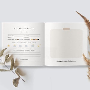 May include: A white book with a brown cover and the text "Hallo kleiner Mensch" and "Dein Name" on the front. The book has a blank page with the text "Willkommen Zuhause" on the bottom.