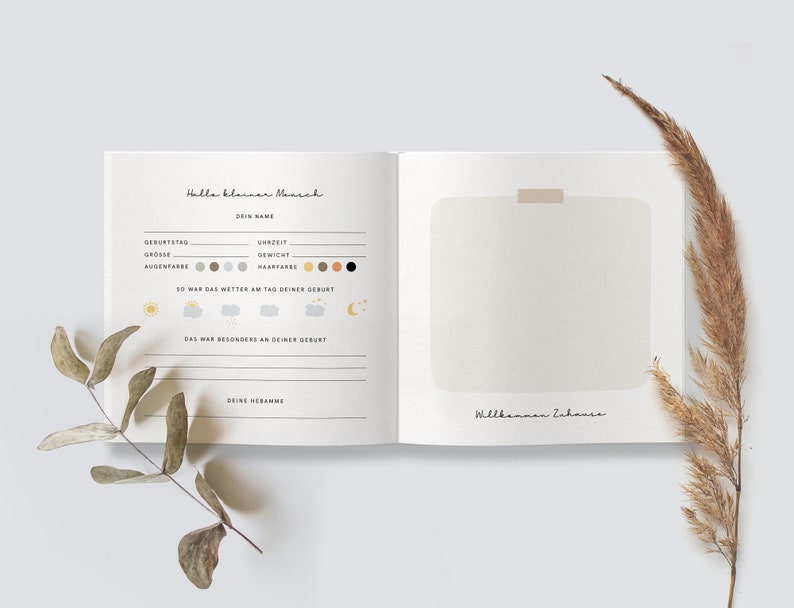 May include: A white book with a brown cover and the text "Hallo kleiner Mensch" and "Dein Name" on the front. The book has a blank page with the text "Willkommen Zuhause" on the bottom.