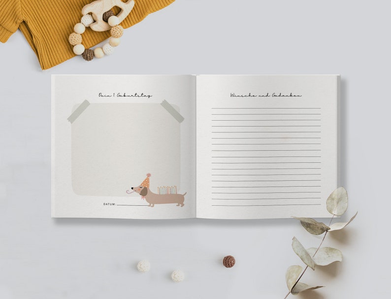 May include: A white book with a brown dachshund wearing a party hat and holding candles. The book has the text "Dein 1. Geburtstag" on the left page and "W&uuml;nsche und Gedanken" on the right page.