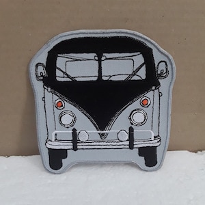 Op de afbeelding: Een geborduurde patch van een vintage Volkswagen busje. De bus heeft een grijs lichaam, een zwart dak en witte koplampen.