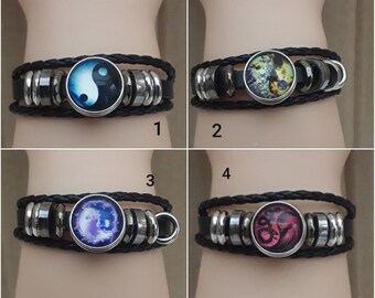 Può includere: Quattro braccialetti in pelle nera con cabochon di vetro di diversi colori. I cabochon presentano un simbolo yin yang, un design floreale colorato, un simbolo yin yang viola e blu e un design di drago rosso e bianco.