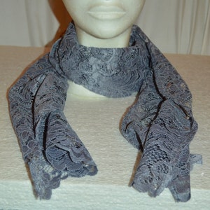 May include: A gray lace scarf with a delicate floral pattern. The scarf is draped around a mannequin's neck.