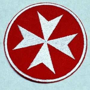 Peut inclure: Un écusson brodé rouge avec une croix de Malte blanche au centre. L'écusson est circulaire et a une bordure blanche.