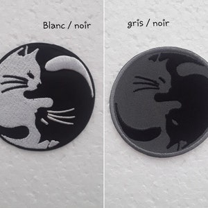 May include: Two embroidered iron-on patches depicting a yin yang symbol with two cats facing each other. The left patch is black and white, and the right patch is gray and black. The text "Blanc / noir" is above the left patch, and the text "gris / noir" is above the right patch.