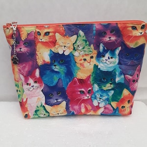 May include: A colorful zippered pouch with a print of many cats in various shades of blue, pink, purple, orange, and green.