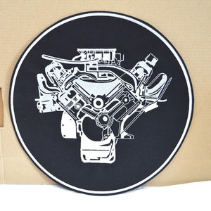 Può includere: Una toppa ricamata in bianco e nero di un motore di auto su uno sfondo circolare nero.