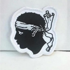 Peut inclure: Patch brodé noir et blanc d'une tête de personne avec un bandeau blanc. La personne est tournée vers la gauche et porte un bandeau blanc autour de la tête.