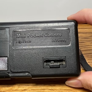 May include: Black Mini Pocket Camera with a flip flash and a JCPenney label.