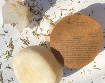 May include: A brown paper wrapped bar of shampoo and body soap with the text "The Herbalist's Assistant" and "Air Shampoo & Body Bar" printed on the label. The ingredients list includes shea butter, coconut oil, and lemongrass.