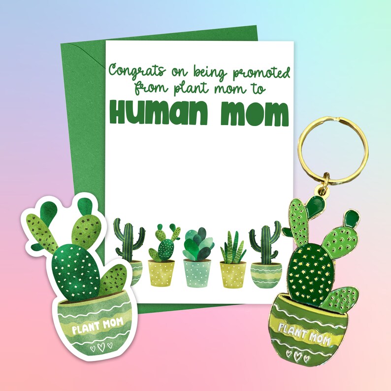 May include: A green card with the text "Congrats on being promoted from plant mom to Human mom".  The card is decorated with a row of potted cacti and succulents.  A green cactus keychain with the text "Plant Mom" is attached to a gold key ring.