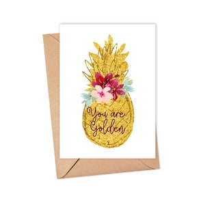 May include: A gold glitter pineapple with pink and red flowers on top. The text "You are Golden" is written on the pineapple.