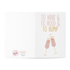 May include: A humorous greeting card with a pink and gold design. The card features two champagne flutes clinking together and the text "To Have & To Hold & To Hump".