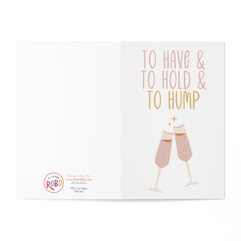 May include: A humorous greeting card with a pink and gold design. The card features two champagne flutes clinking together and the text "To Have & To Hold & To Hump".