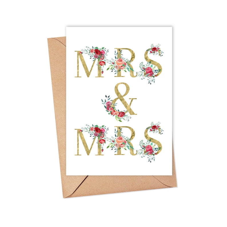 May include: A white card with a gold floral design that reads 'MRS & MRS' in gold letters with floral accents.