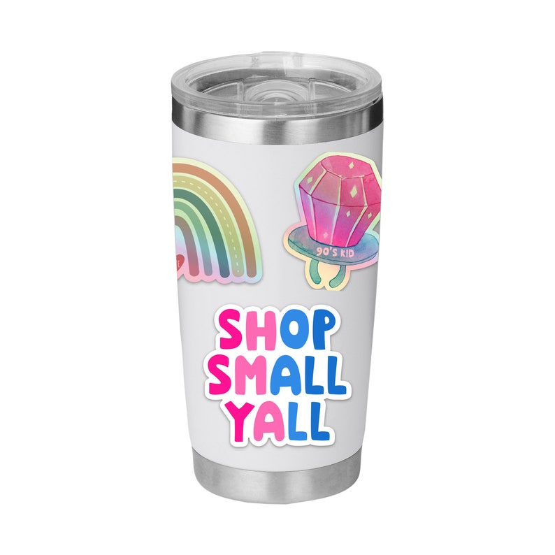 May include: A white insulated tumbler with a silver lid, featuring colorful stickers. Stickers include a rainbow, a pink and purple ring pop with "90's Kid" text, and the text "SHOP SMALL YALL" in pink and blue.