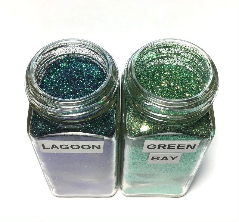 K&ouml;nnte beinhalten: Zwei Glasbeh&auml;lter gef&uuml;llt mit gr&uuml;nem Glitter. Der Beh&auml;lter links ist mit "LAGOON" beschriftet und der Beh&auml;lter rechts mit "GREEN BAY".