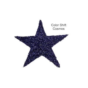 May include: A dark blue, glittery star shape against a white background. The star is filled with small, reflective particles, creating a shimmering effect. Text on the image reads "Color Shift Cosmos."