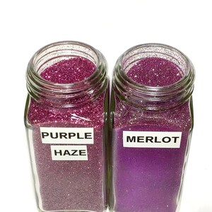 K&ouml;nnte beinhalten: Zwei Glasbeh&auml;lter gef&uuml;llt mit lila Glitter. Der Beh&auml;lter links ist mit "Purple Haze" beschriftet und der Beh&auml;lter rechts mit "Merlot".