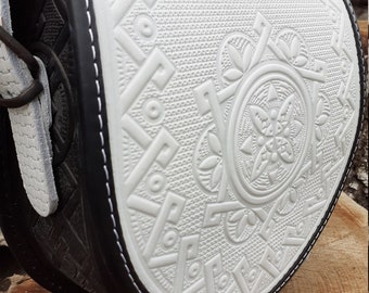 Può includere: Borsa a tracolla in pelle bianca con bordatura nera e un design geometrico in rilievo. La borsa ha una chiusura a lembo e una tracolla.