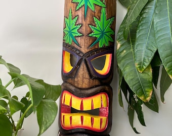 May include: A wooden tiki mask with a carved face and green marijuana leaf designs. The mask has a red mouth with yellow teeth and the text "It's 4:20 Time" written below.
